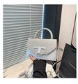 Details der silbernen Handtasche mit Glitzerklappe und weißem T-förmigem Emblem - Silber