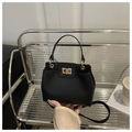 Primer plano del bolso de piel negra con textura lichi y elegante cierre de giro dorado - Negro