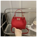 Detalle del bolso tipo cubo rojo en cuero granulado con cierre metálico giratorio - Rojo