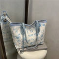 Borsa tote graffiti blu con orso e manici in pelle su uno sgabello bianco - Blu