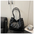 Black tote bag with woven handles and quilted texture displayed on a modern black sofa - Black (Without Charm)