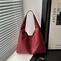 Bolso hobo minimalista de cuero granulado rojo mostrado bajo luz suave de ventana - Rojo (Textura Lichi)