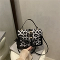 Sac bandoulière tendance en fausse fourrure léopard noir et blanc avec boucle dorée - Noir