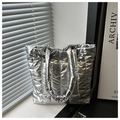 Primer plano de bolso tote plateado acolchado con textura suave y brillo metalizado - Plateado