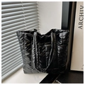 Detalle del bolso tote acolchado negro brillante que muestra tela y textura - Negro