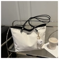 Detail of cream tote bag with black handles, metal logo and plush monster charm decoration - White With Pendant