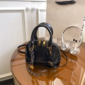 Glossy black shell bag with crocodile texture and gold hardware on a lifestyle setup - With Bell Woven Pendant / Black