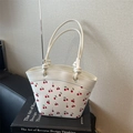 Minimalistische weiße Beuteltasche mit Kirschprint und Knotengriffen auf Kunstbuch - Gebrochenes Weiß