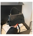 Detail showing wavy edge flap and gold hardware of the matte black square handbag - Black