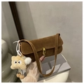 Close-up of brown suede underarm bag with gold metal lock and a cute plush charm - Brown with Pendant