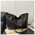 Detail of black large capacity leather tote bag placed on beige textured fabric - Black