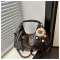 Dettaglio di borsa tote vintage marrone scuro con ciondolo a forma di agnello su davanzale - Caffè con Ciondolo