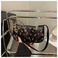 Detail of black baguette bag featuring red cherry print and golden chain handle - Black