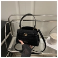 Detalle de bolso negro con patrón de cocodrilo y elegante cierre de metal dorado - Negro