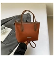 Detail van de karamelkleurige bucket bag van kunstleer met zilveren Fashion-logo en textuur - Bruin