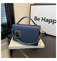 Detail of dark blue leather handbag featuring gold geometric buckle and woven chain strap - Blue