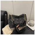 Detail of grey checkered canvas tote with gold chain strap and fringed edges on a chair - Black