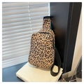 Detail of leopard print crossbody bag with black zipper and adjustable strap on book - Leopard Print