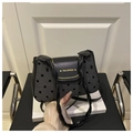 Detail of grey polka dot fabric texture and black leather flap with golden brand logo - Black