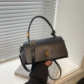 Bolso bandolera negro chic con cierre giratorio dorado y asa con nudo en un ventanal - Negro