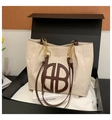 Dettaglio della borsa tote in tela con finiture in pelle marrone e catena d'oro in regalo - Bianco