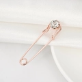 Elegant rose gold crystal safety pin brooch displayed on white silk and ceramic plate - Rose Gold