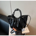 Detail of black pleated cloud bag showing glossy patent leather and sturdy round handles - Black