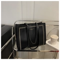 Détail du sac cabas noir texturé avec lettrage doré exposé sur une étagère métallique - Noir
