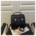 Detalle de textura tejida en mochila de cuero negro con elegante hebilla metálica dorada - Negro