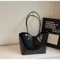 Detail of glossy black leather tote bag featuring elegant gold metal strap connectors - Black
