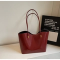 Deep red patent leather tote bag detail with luxury gold hardware and minimalist design - Burgundy