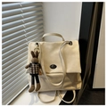 Détail d'un sac à dos beige en cuir souple avec fermoir métallique et breloque lapin - Blanc Crème avec Pendentif