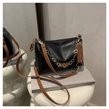 Close-up of black leather crossbody bag with golden flower chain and fashion tag - Black