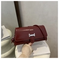 Detalle de bolso en cuero burdeos con hebilla plateada y elegantes nudos en la correa lateral - Rojo