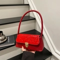Chic red faux crocodile skin underarm bag with gold clasp shown in lifestyle setting - Red