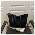 Detalle de bolso tote minimalista de ante negro con asas finas en silla de metal negra - Negro