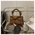 Bolso marrón con lazo y asa trenzada sobre una silla para un estilismo muy elegante - café
