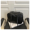Minimalist black matte Boston handbag with silver zipper shown on a modern black chair - Black