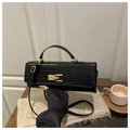 Détail d'un sac à main noir en cuir façon crocodile avec fermoir doré sur table en bois - Noir