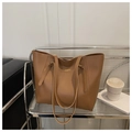 Primer plano de bolso tote en cuero marrón sobre estante con taza de café y libros - Marrón
