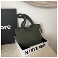 Detail showing dark green corduroy tote bag texture with side pocket and cord knot - Green