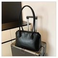 Minimalist black leather tote bag for women placed on a silver suitcase for commuting - Black