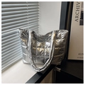 Detailed view of silver quilted metallic tote bag placed against a minimalist window - Silver