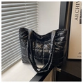 Close-up of black quilted puffer tote bag featuring glossy waterproof nylon material - Black