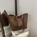 Classic brown leather tote bag with gold branding on a white stool, home aesthetic - Brown