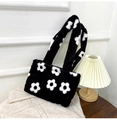 Detalle del bolso de peluche con flores sobre manta con luz cálida ambiental - Negro