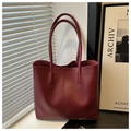 Detalle de un bolso tote de cuero rojo oscuro con costuras verticales y luz natural - Conjunto De Dos Piezas De Bolso Tote Y Bolso De Mano / Rojo