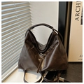 Detail der dunkelbraunen Leder-Tote-Tasche mit Metallschließe bei sanftem Fensterlicht - Kaffeebraun
