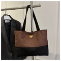 Détail du sac cabas contrasté avec emblème triangle doré et texture aspect daim fin - Café Sans Pendentif