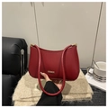 Dettaglio borsa a tracolla in pelle rosso scuro con finiture dorate su sfondo neutro - Rosso